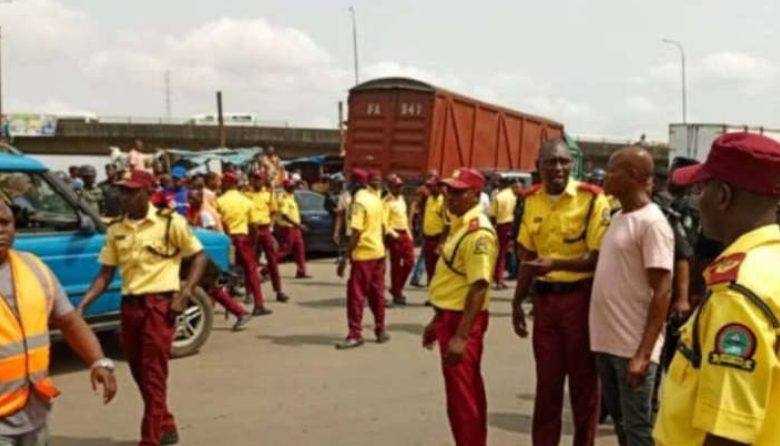 A busy Lagos highway with heavy traffic congestion, emergency responders at a crash scene, and LASTMA officers managing traffic flow during peak hours.